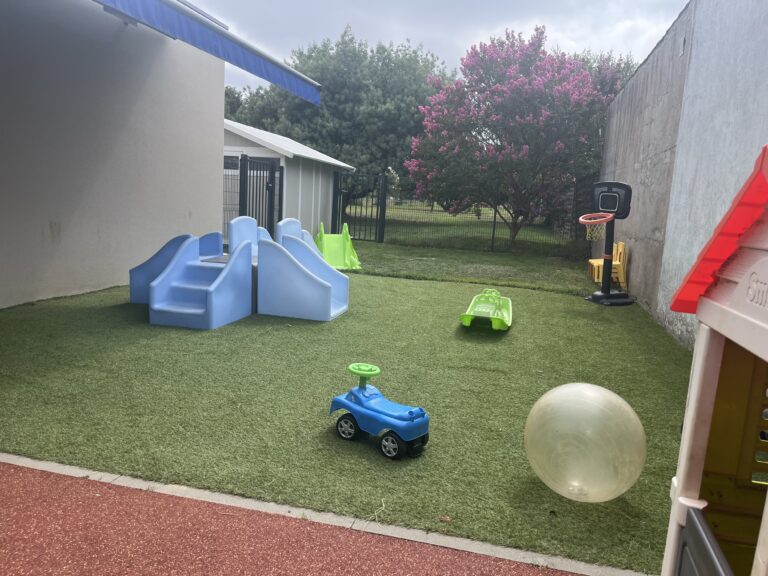Aire de jeux extérieure de la micro-crèche MON JARDIN D’ÉVEIL à Bouguenais, avec toboggans, petite voiture, ballon et coin nature.